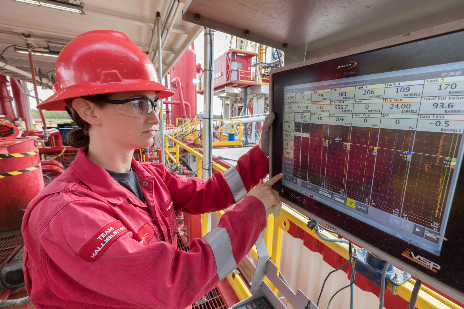 A Halliburton engineer looking at data on a screen.