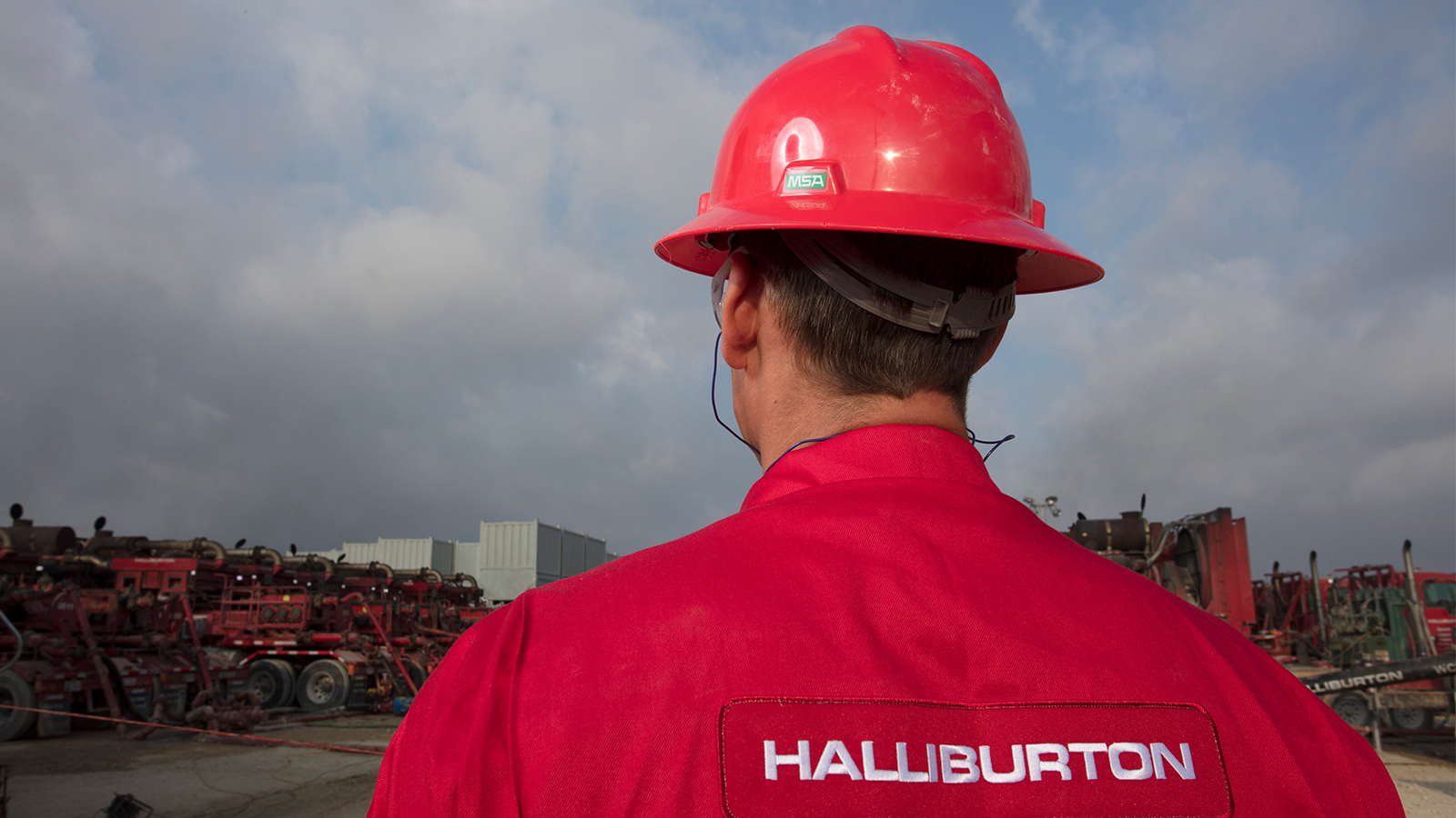 A man with halliburton t-shirt and a red cap