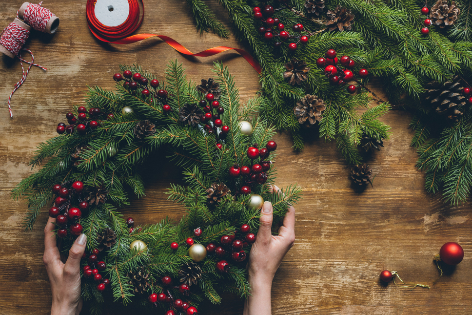 Female hands holding a Christmas wreath on a wooden tabletop