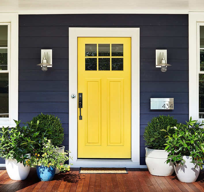 Bright yellow entry door on a blue home