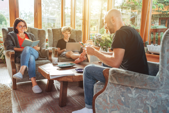 Mother, father, and child sitting together in a sunroom