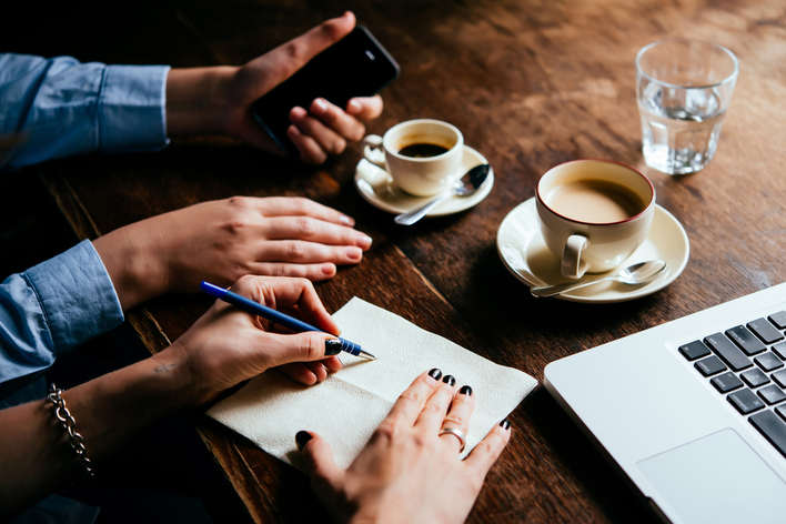 Couple filling out paperwork with coffee and laptop