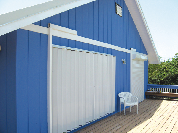 Blue house featuring white accordion shutters on the windows and entry door