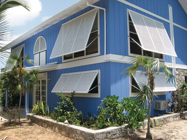 Blue house with white Bahama Shutters on windows