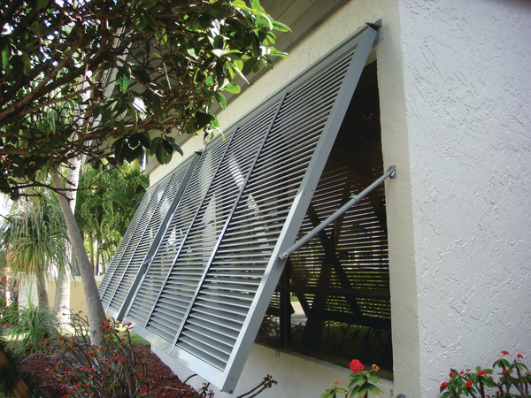Side shot of house with large Bahama Shutters on windows