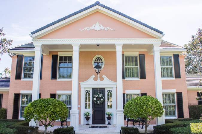 Black louvered Colonial Shutters on a salmon-colored colonial home