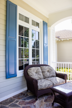 Blue raised panel Colonial Shutters shown on an ivory-colored house's porch