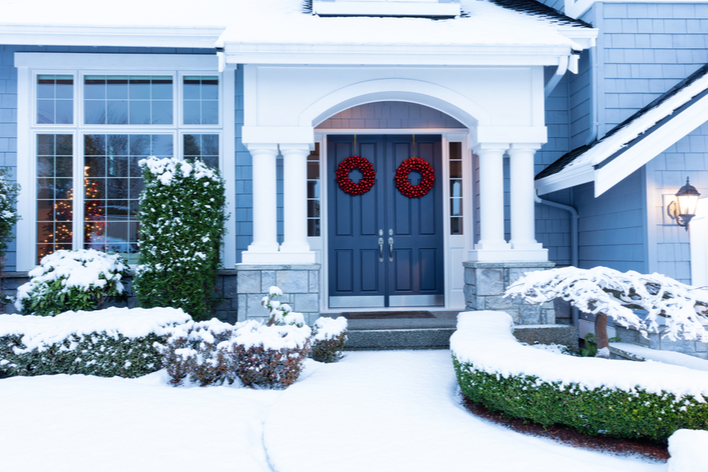 Red Christmas wreaths on a blue double front door