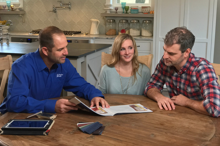 Happy couple sits with a professional contractor to discuss their home remodel