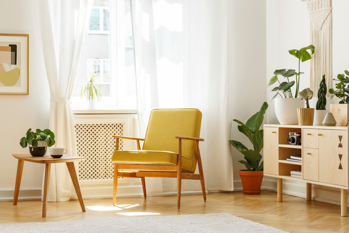 A mid-century modern yellow chair in a room with plants and other modern home design features