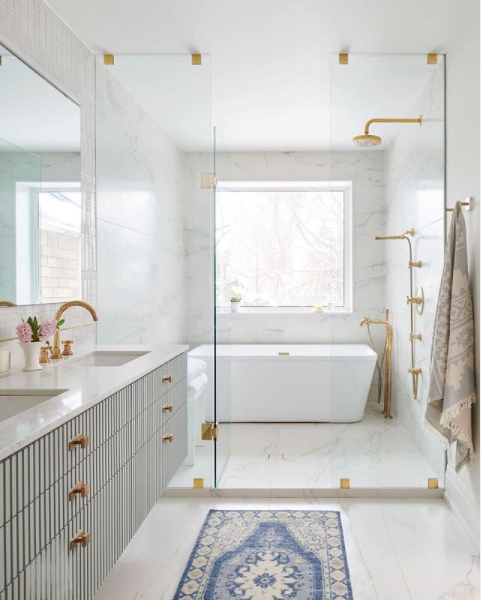 A beautiful bathroom with glass shower enclosure and brass hardware