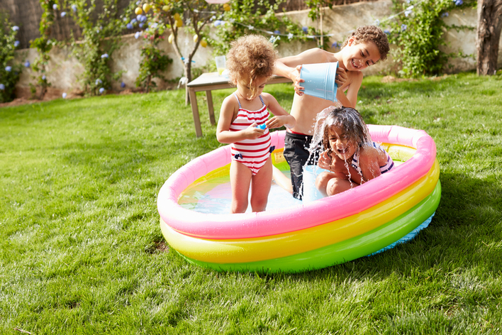 Kids playing in the backyard in an inflatable pool