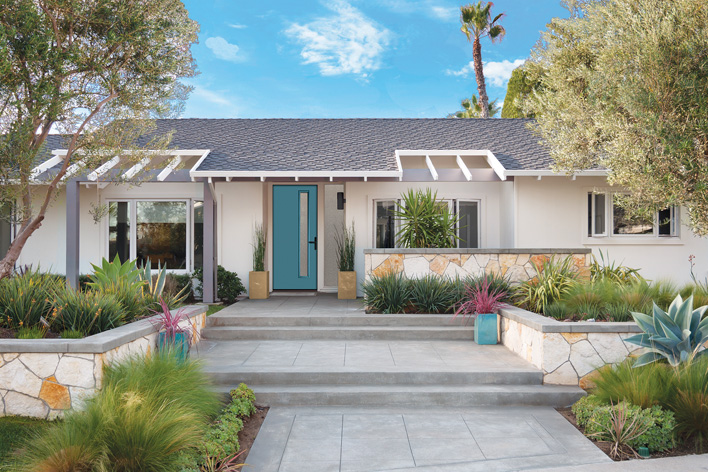 A mid-century modern home with exterior features that include a modern teal door and a linear landscape design