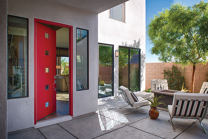 The exterior of a mid-century modern home that includes an outdoor living space and a modern red door