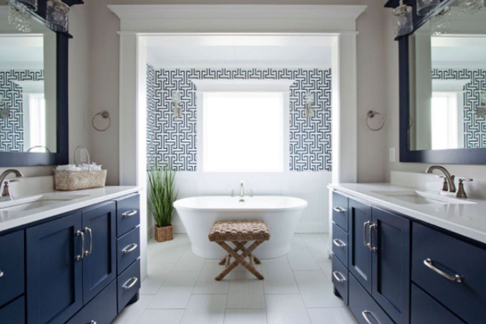 A large bathroom with matching blue vanities and white bathtub