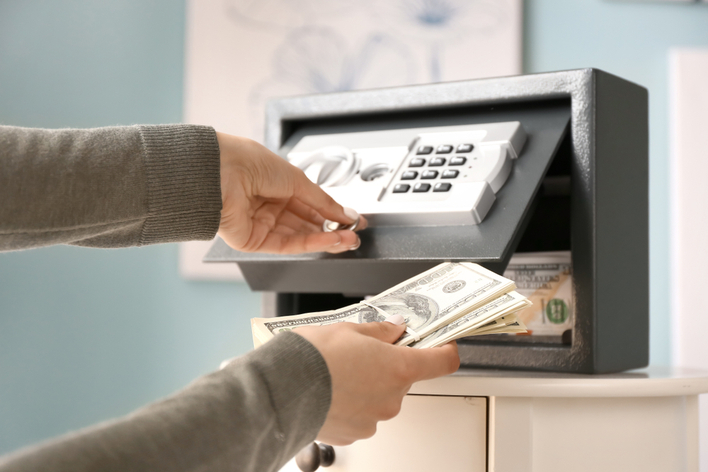 Woman putting money in a personal safe 