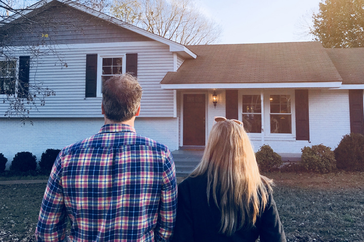 Man and woman looking at the exterior of a split-level home