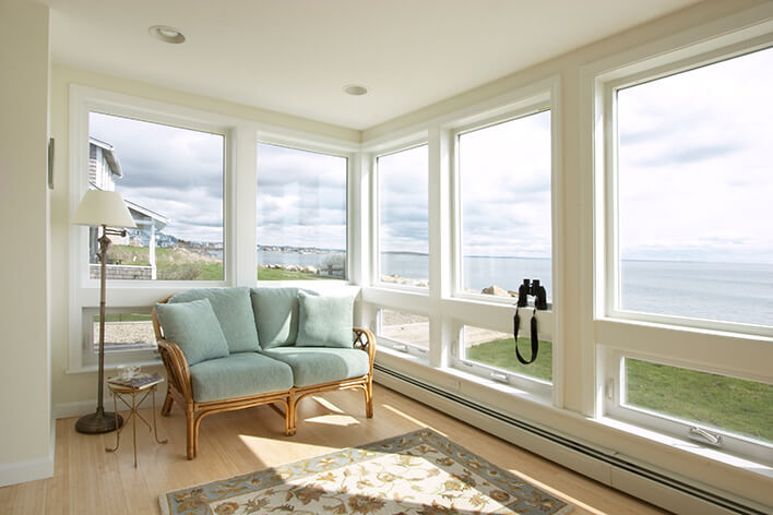 A sunroom with large casement windows providing beach views