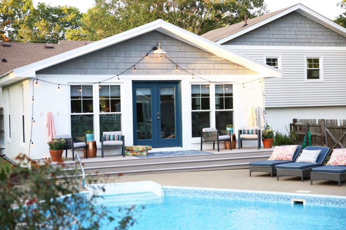 Backyard view of a split-level house with a pool in the foreground