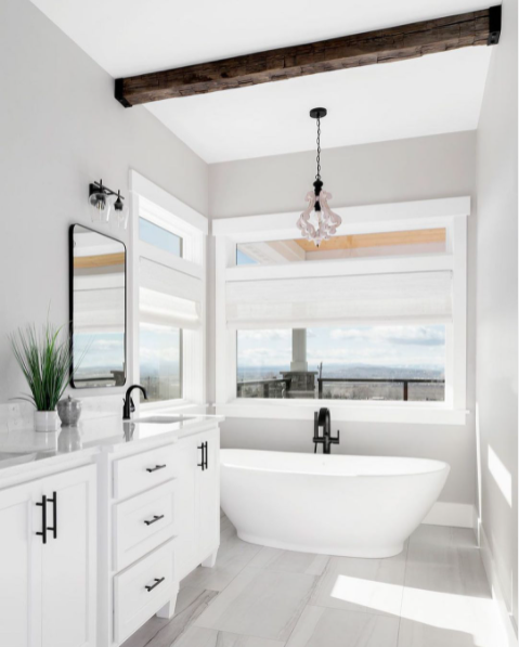 A charming bathroom with large windows, an exposed beam, and a comfy tub