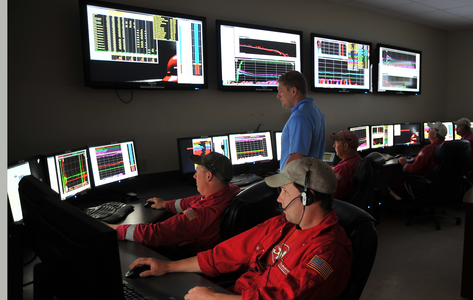 Four halliburton engineers looking at the data on the screen.