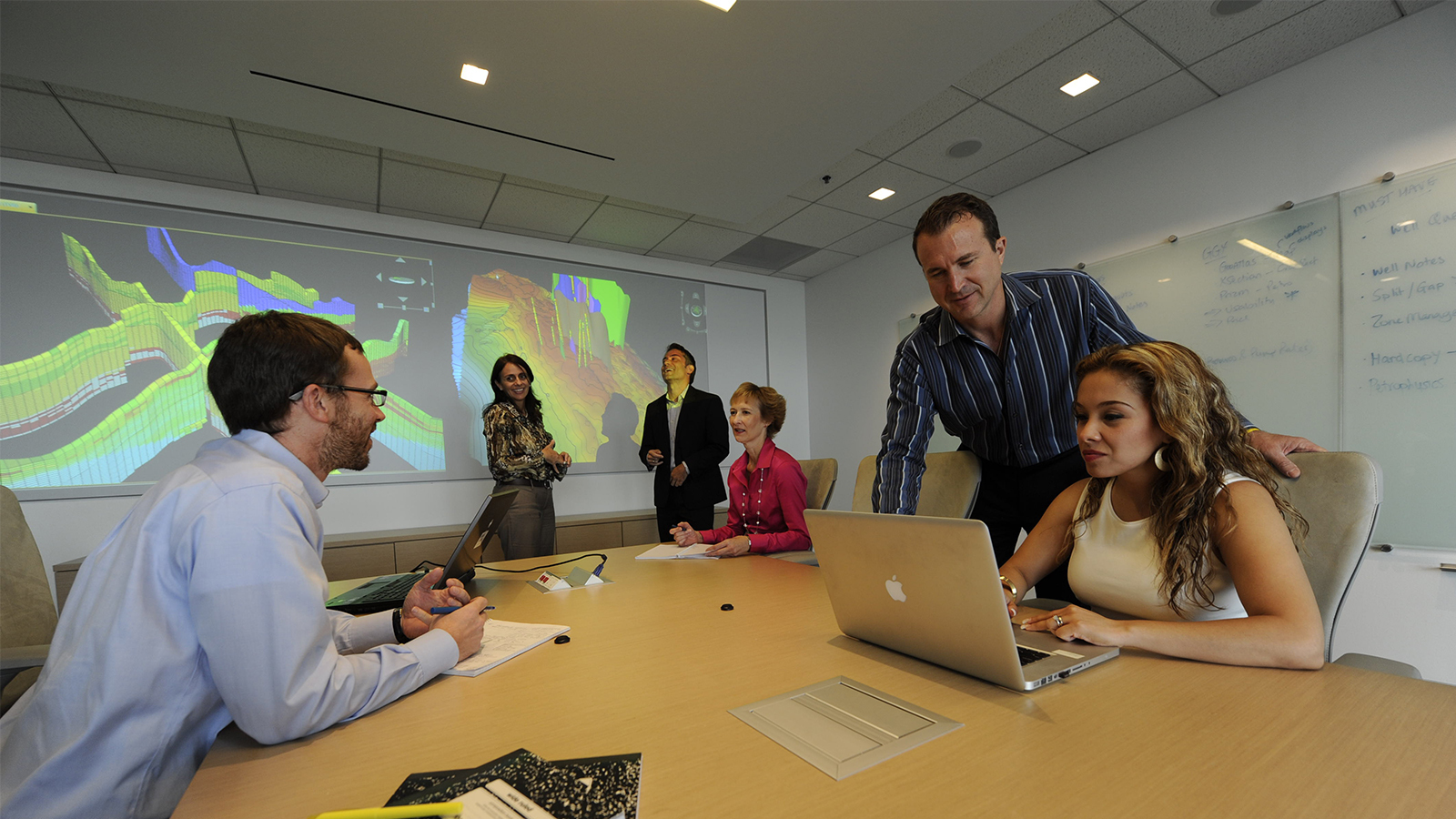 Halliburton employees in a meeting reviewing data on the screen