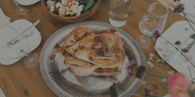 A cooked turkey on a platter in the middle of a festive dinner table