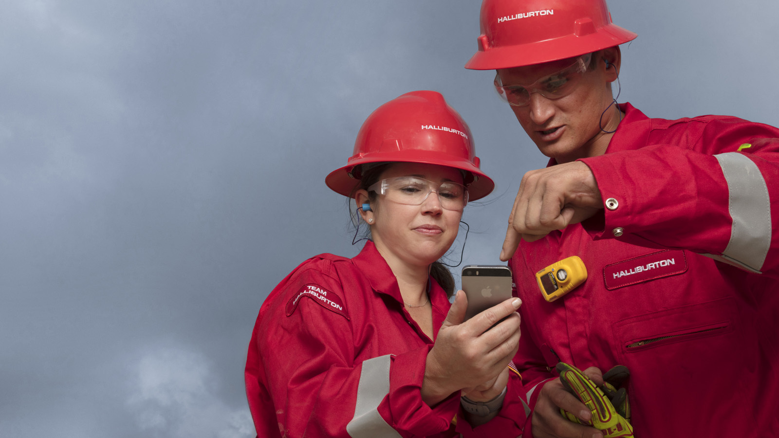 Two halliburton engineers looking at a phone