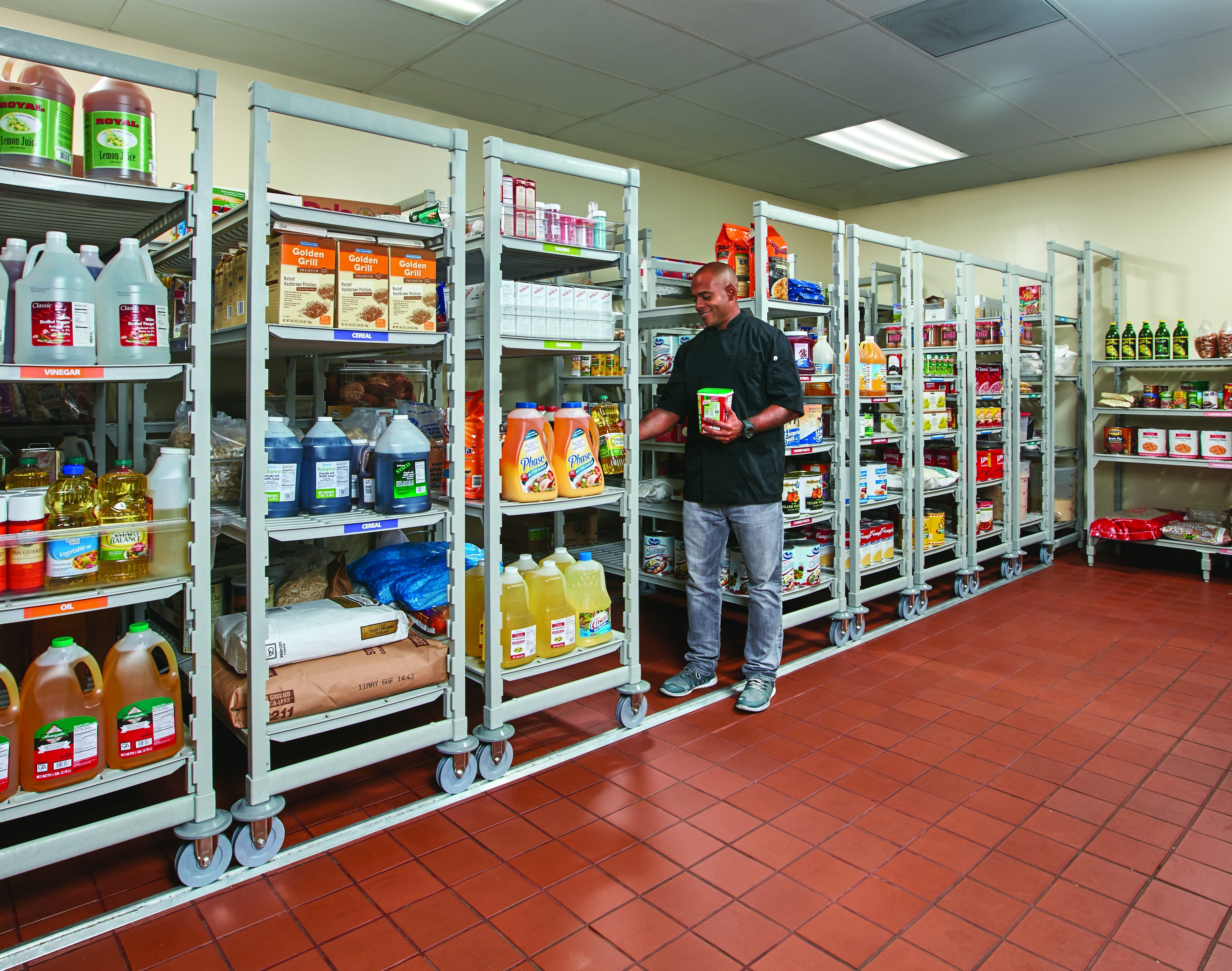 A chef pulling contents from a high density shelving unit lined up on a track to save space