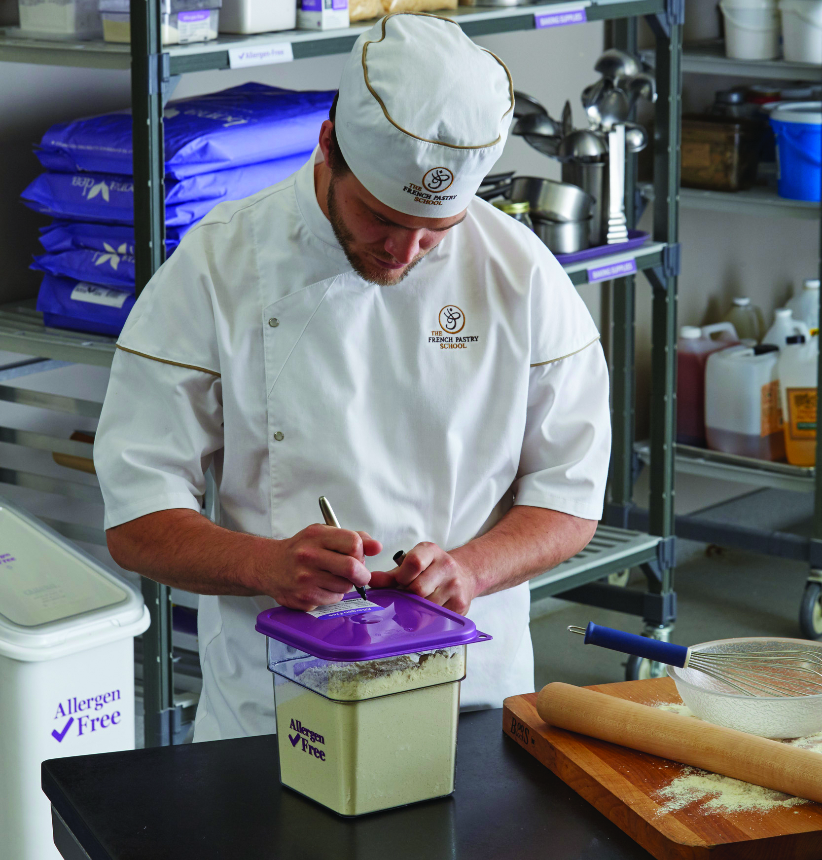 A chef writing on a StoreSafe label on top of a purple Allergen-Free CamSquare