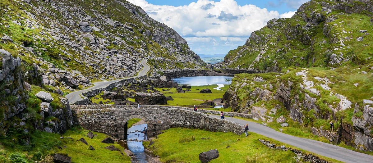 Winding road through a green mountain pass and lake on Britain and Ireland in Depth tours.