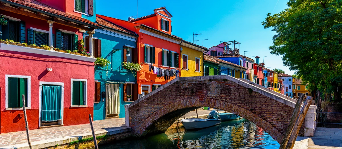 Brightly coloured houses along a canal in Burano on a middle school Explore Italy tour.