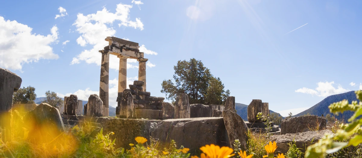 Ancient Greek ruins at Delphi under a blue sky, visited on student tours of Greece and Italy.