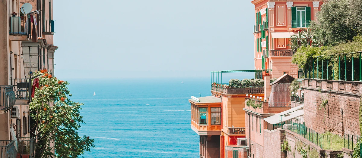 Colourful cliffside buildings above a blue sea on the European Showcase student tour.