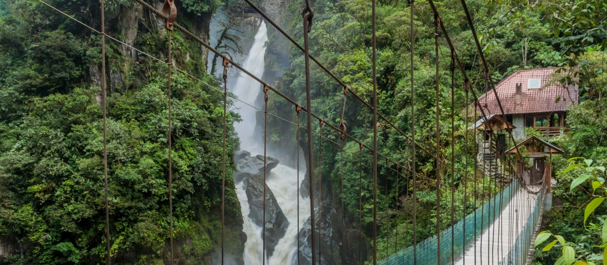 Suspension bridge in front of a rainforest waterfall in ecuador.
