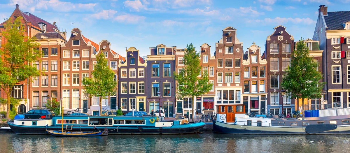 Amsterdam canal houses and moored houseboats on Amsterdam and Paris student tours.