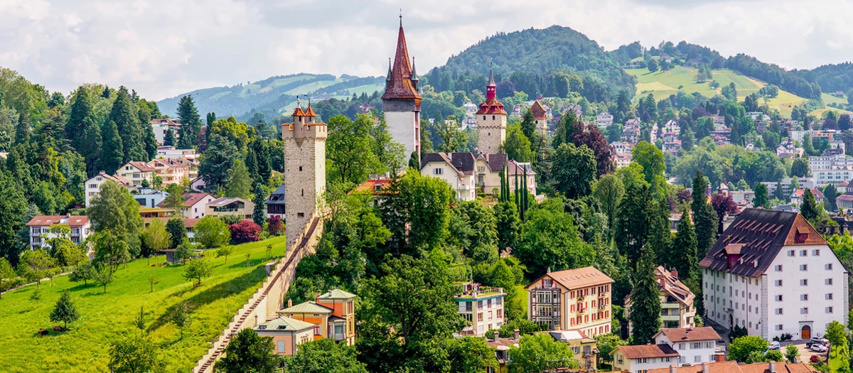 Medieval towers above a Swiss town and green hills on France, Switzerland and Italy tours.