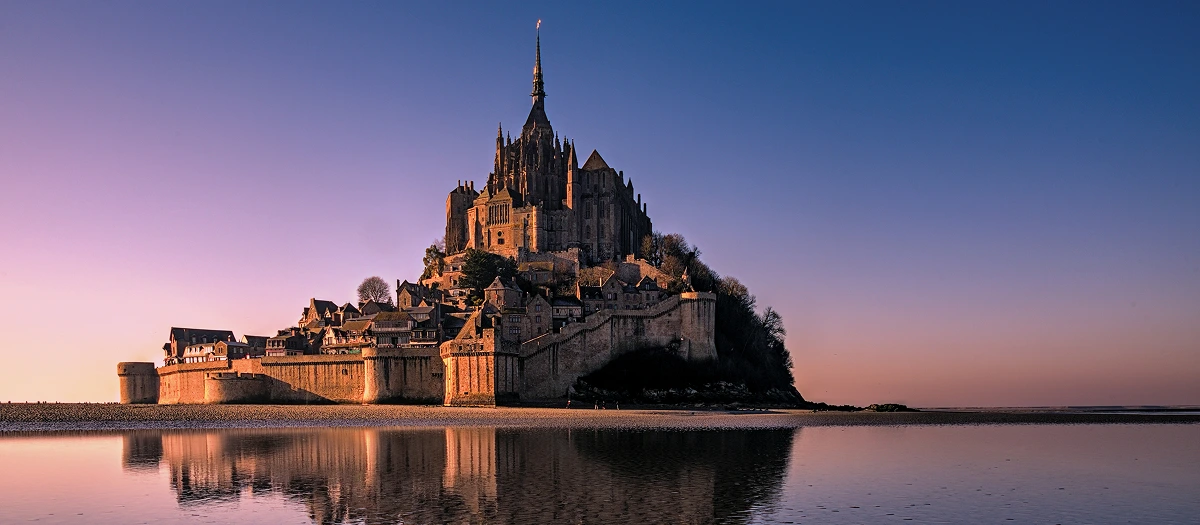 Mont Saint-Michel rising from the bay at dusk in France on a Paris and chateaux tour.
