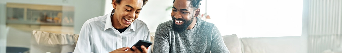 father and son seating together looking at phone