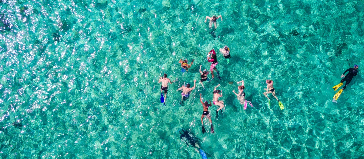 Snorkellers swimming in clear turquoise water in Belize on the Impressions of Belize tour.