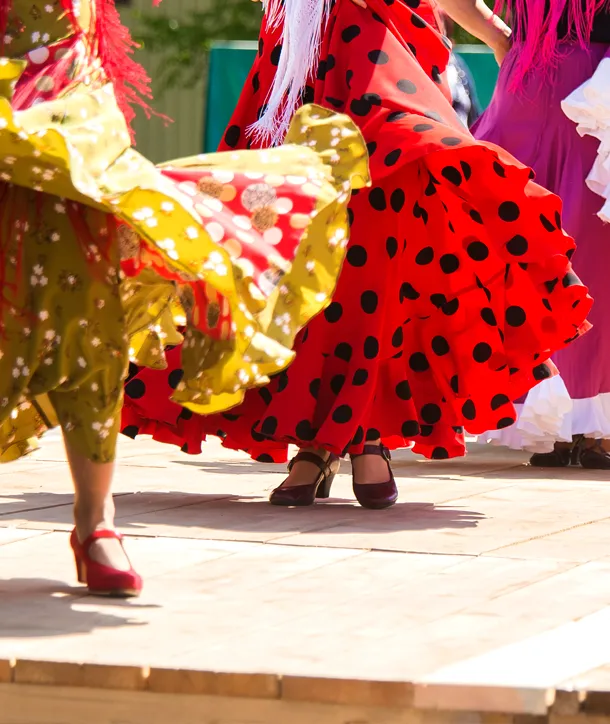 Spanish fiesta close-up: Two women with colorful dresses dancing.