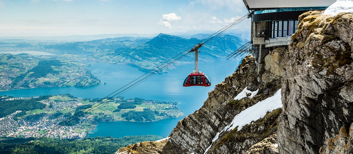 Red cable car climbing above an Alpine lake on Germany and the Alps student tours.