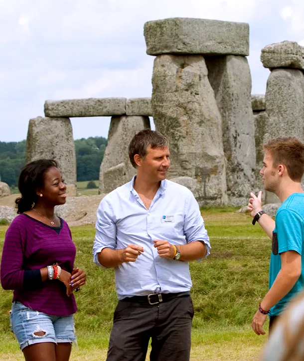 Teacher conversing with students in front of Stonehenge on STEM London tour.