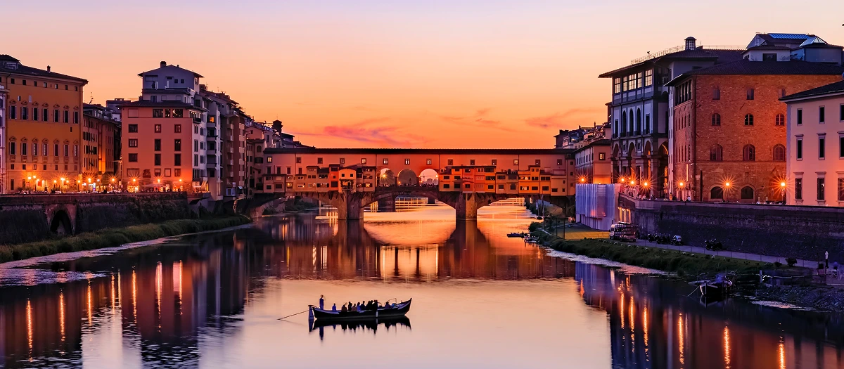 Ponte Vecchio reflected in the Arno at sunset in Florence on Paris and Italy tours.