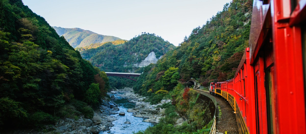 Red train along a river in Japan