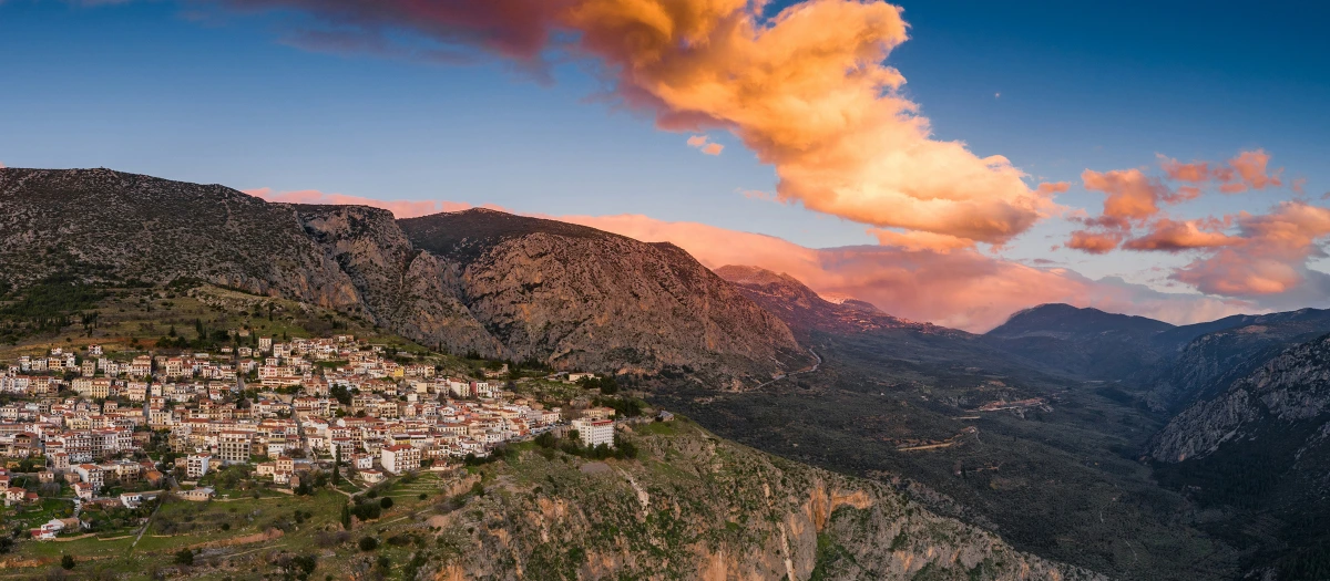 Hillside village below rugged mountains at dusk in Greece on the Epic Greece student tour.