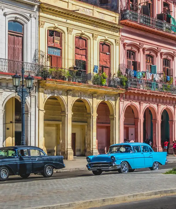 Colorful buildings with two antique cars captured on an EF Cuba tour.