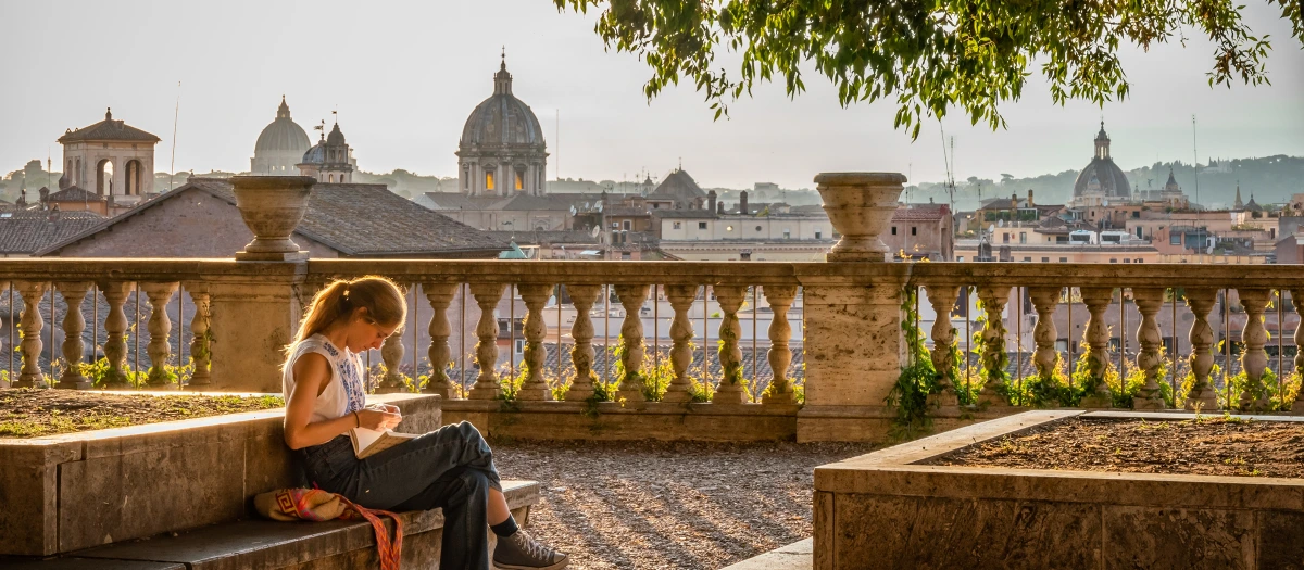 Student sketching on a terrace above the domes and rooftops of Rome on a Rome to Athens tour.