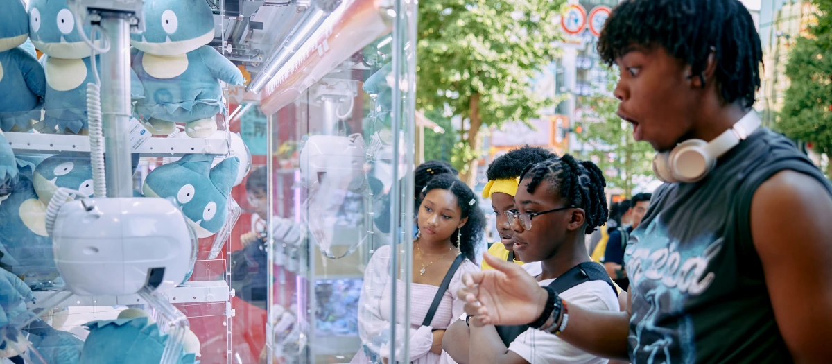 Students in Akihabara electric town in Japan looking at Pokemon game.