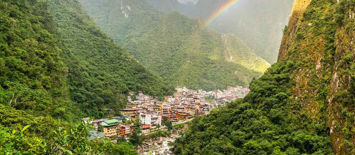Andean valley town below green peaks and a rainbow on a Spanish immersion tour in Peru.